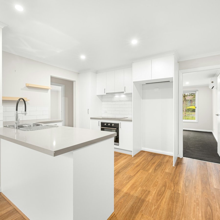 Newly renovated kitchen with white cupboards, a grey benchtop and a timber floor